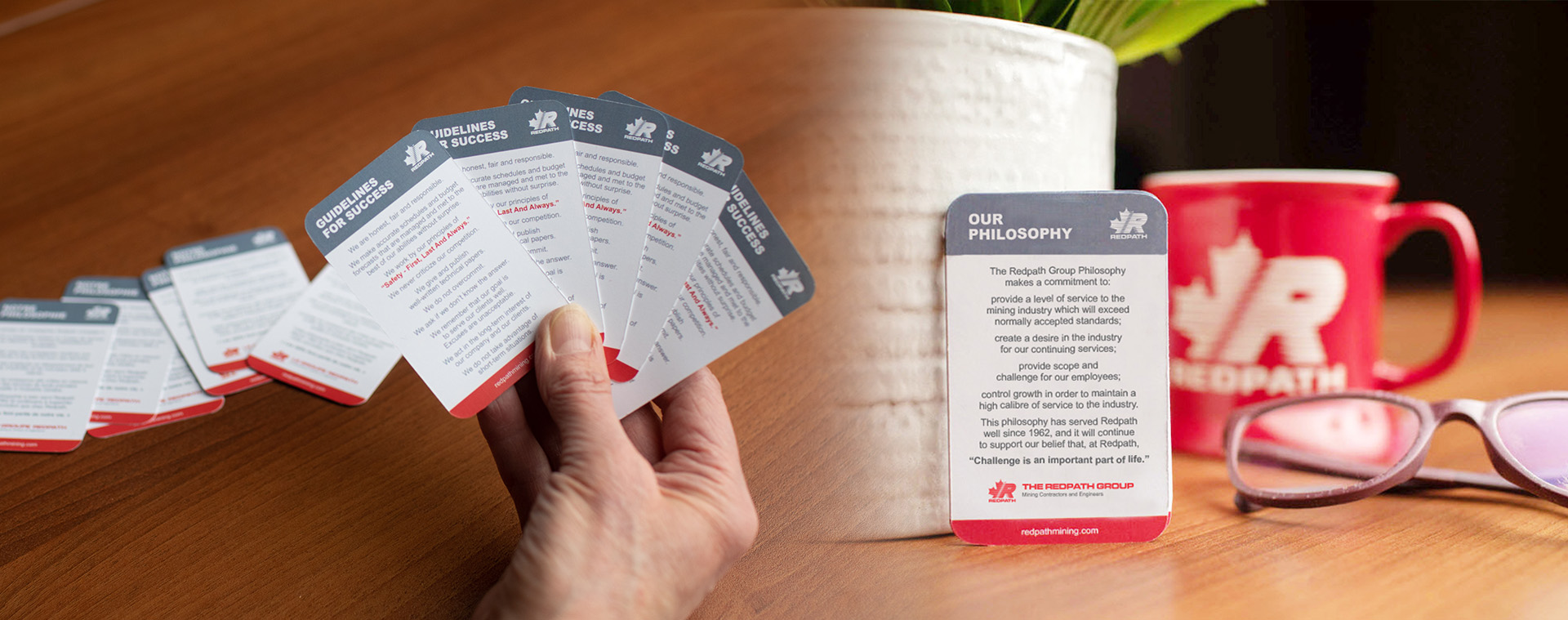 An image of a hand holding the Guidelines For Success and Our Philosophy cards.